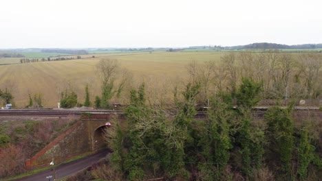 drone footage of a fly pass of a train track in kent countryside with railway track bridge