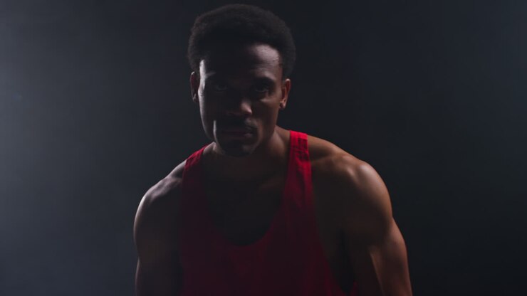 Portrait Of Boxer Entering Ring At Start Of Boxing Match Beating Chest With Glove Warming Up With Low Key Lighting