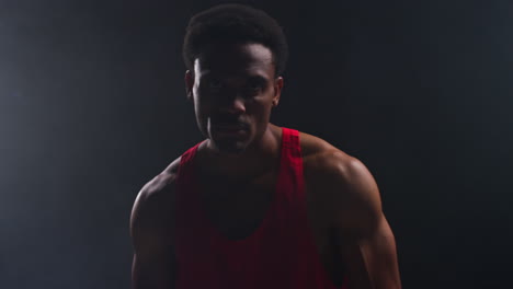 portrait of boxer entering ring at start of boxing match beating chest with glove warming up with low key lighting