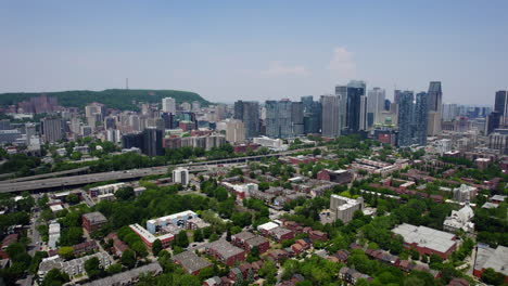 Drone-shot-panning-over-suburbs-toward-the-downtown-skyline-of-sunny-Montreal