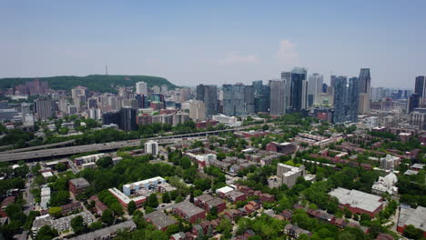 drone shot panning over suburbs toward the downtown skyline of sunny montreal