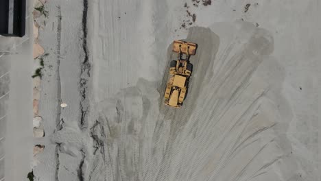 birds eye move of aerial drone footage of two earth movers reshaping sandy beach at cohasset, ma