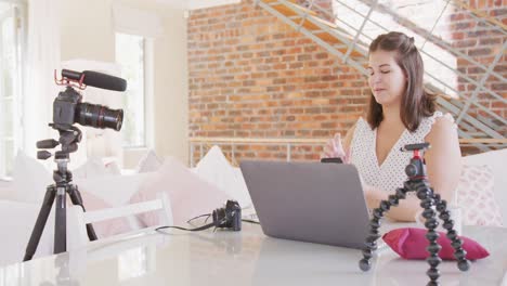 mujer vlogger caucásica haciendo un montaje de video en casa
