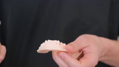 person holding invisalign aligners and dental model