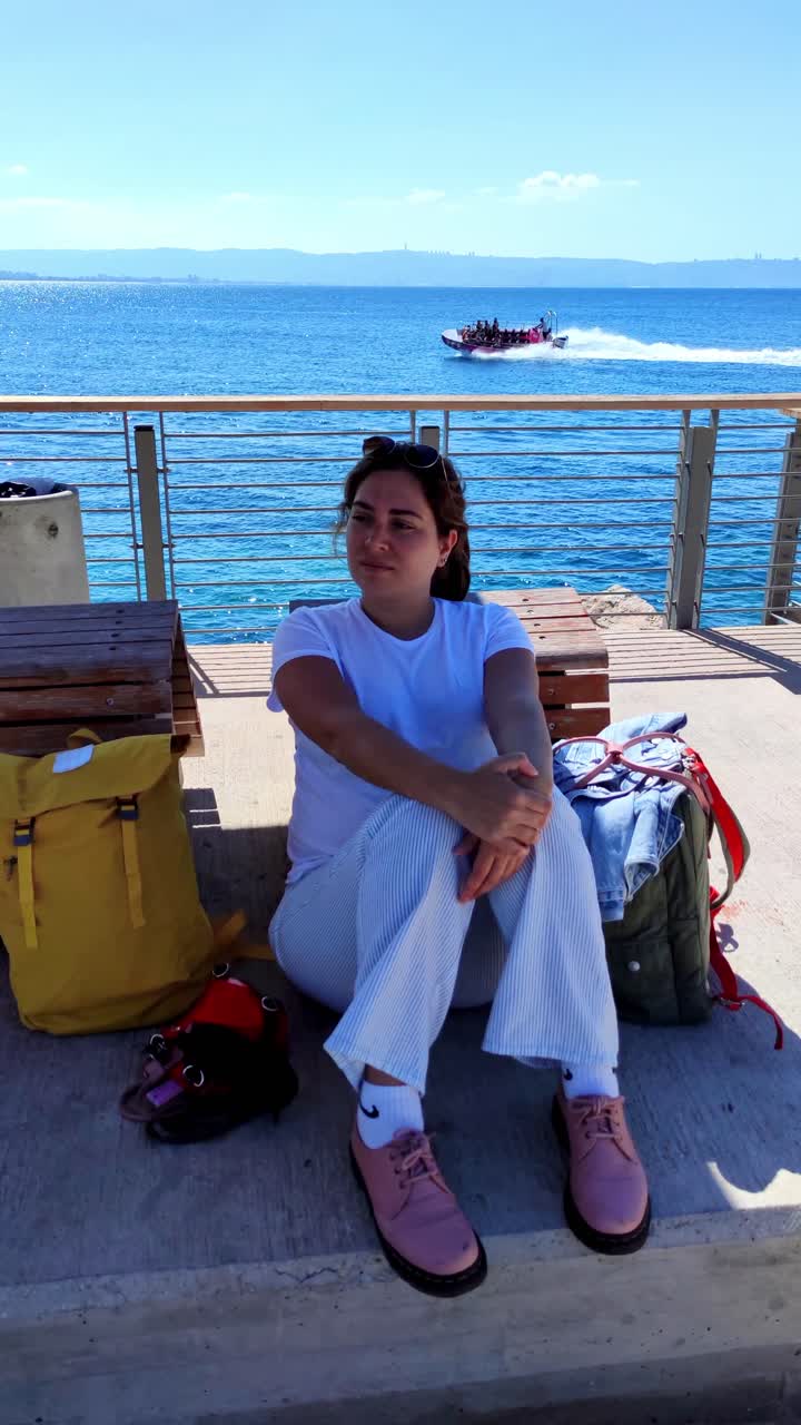 Giovane donna seduta su una panchina che si gode la brezza marina ad Acri