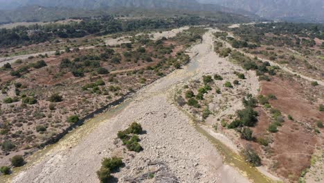 Descending-aerial-shot-tilting-up-to-to-the-dried-Ventura-River-riverbed-in-the-Ojai-Valley,-California