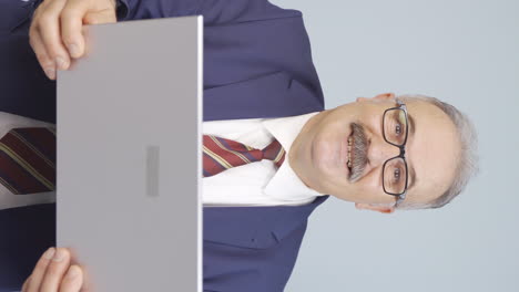 Vertical-video-of-Satisfied-old-businessman-looks-at-laptop-and-approves.