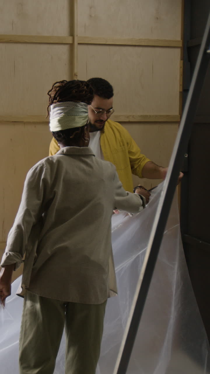 Two people prepare plastic in a workshop