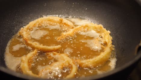 Close-up-of-huge-wok-while-frying-homemade-onion-rings-in-oil-and-deep-pan