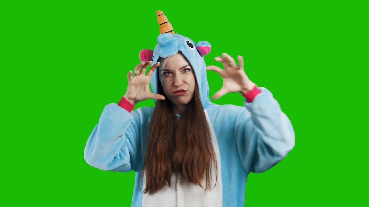 retrato de una linda joven morena en un hermoso disfraz de unicornio en fondo verde clave de cromo. sonriendo y jugando. animador en disfraz. pijama de unicorcio. video 4k con canal alfa