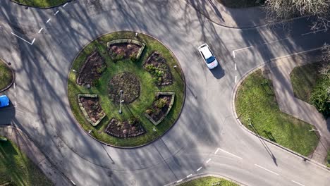 aerial view overlooking vehicles driving around sollershott circus, first traffic roundabout in uk