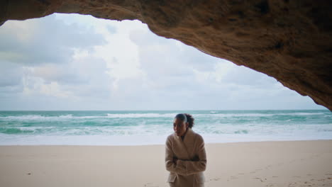 peaceful traveler explore seashore walking beach. curly woman hiding ocean cave