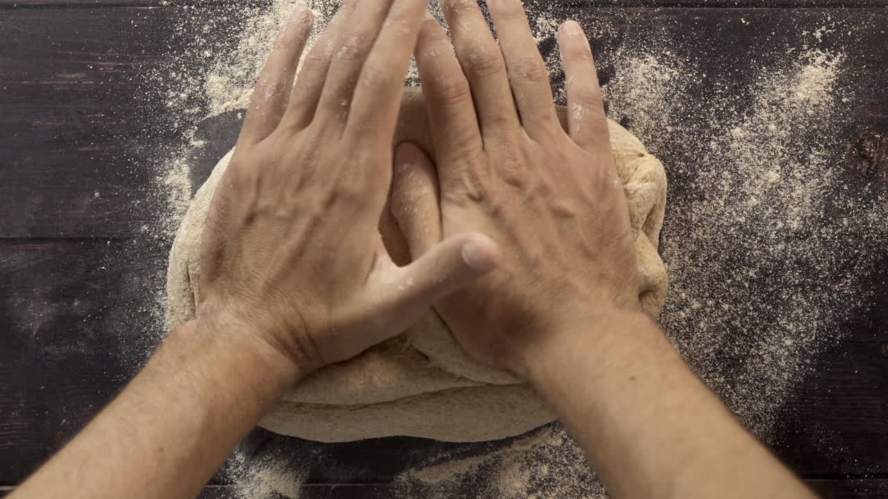 Visuale dall'alto di mani che impastano pasta fresca per cuocere