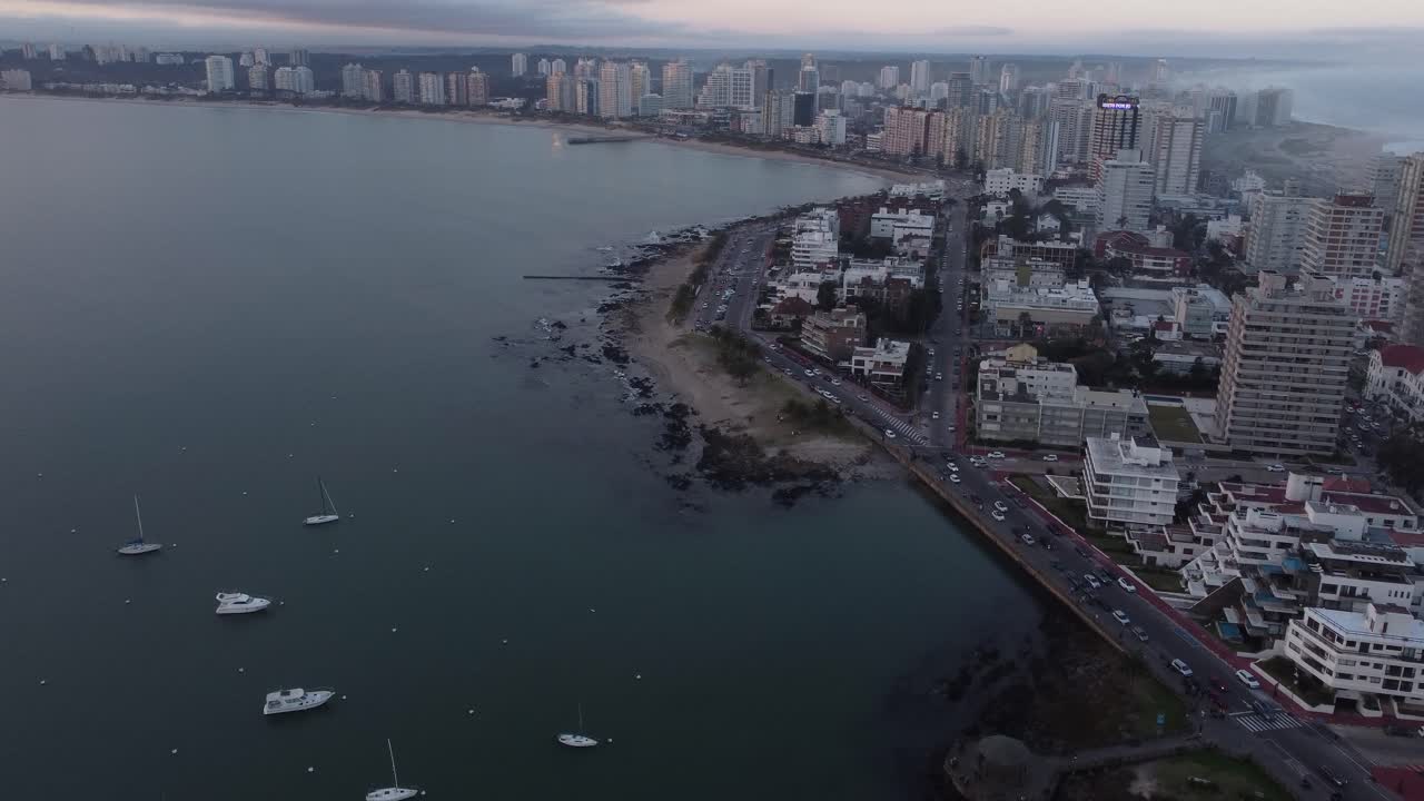 vuelo aéreo hacia adelante sobre barcos amarrados y tráfico en la carretera costera ion playa de punta del este al amanecer