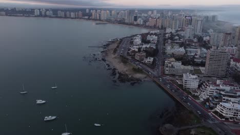 vuelo aéreo hacia adelante sobre barcos amarrados y tráfico en la carretera costera ion playa de punta del este al amanecer