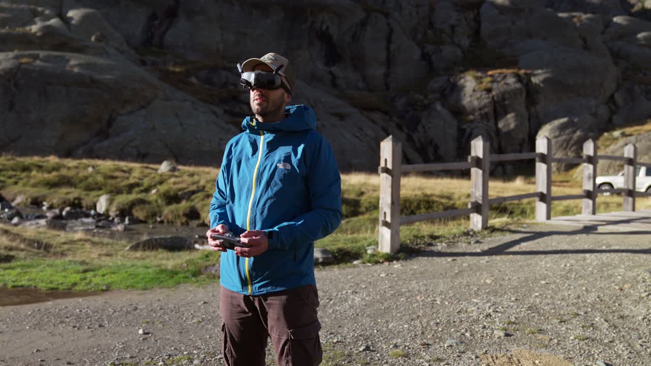 Man wearing virtual reality goggles to operate drone outdoors in the mountains
