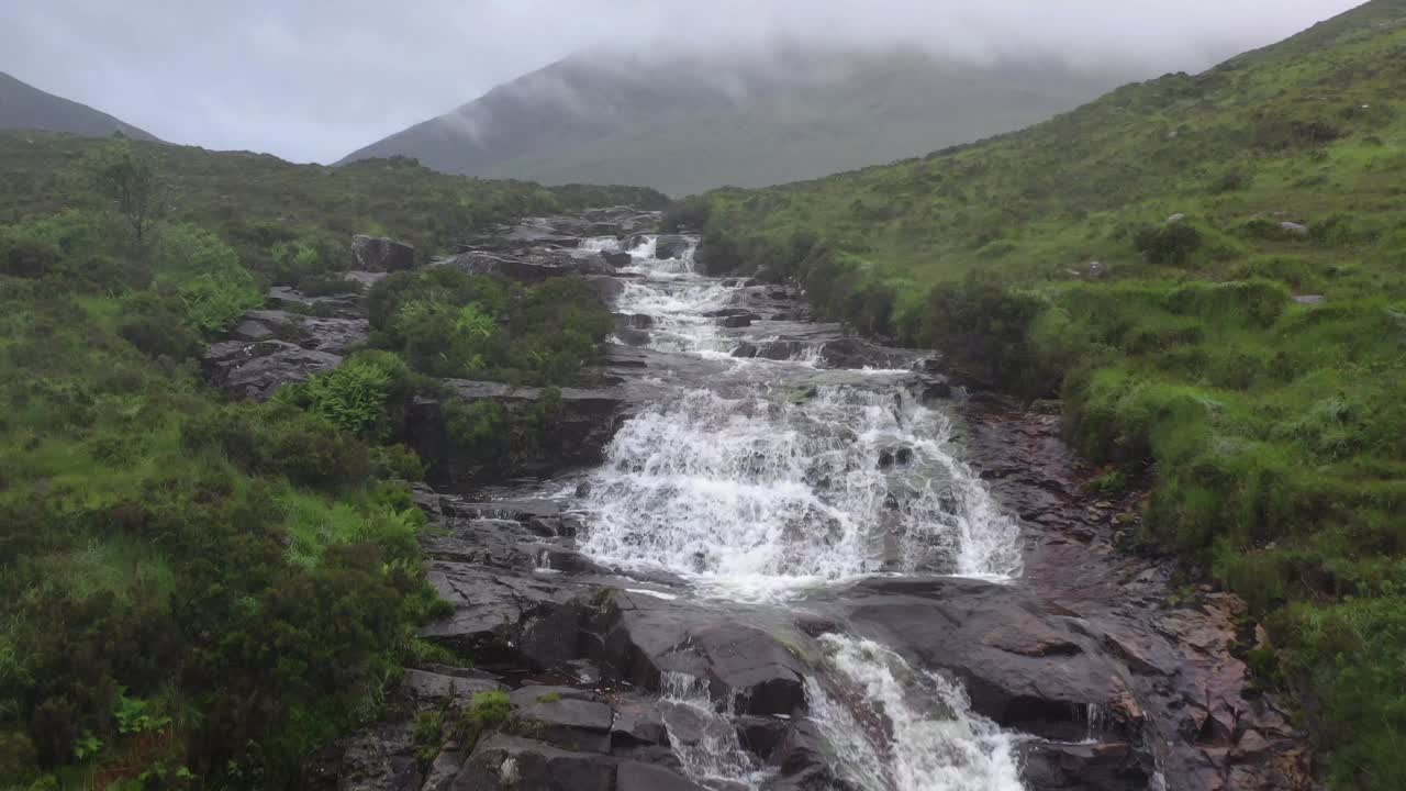 vista aérea de la cascada que cae en cascada por rocas escarpadas en la isla de skye, escocia
