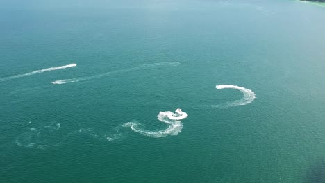 aerial of jet skis doing freestyle tricks in the sea