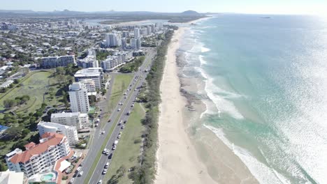 hoteles frente a la playa y coches conduciendo en la carretera a lo largo de la playa de alexandra headland en qld, australia