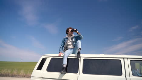 young boy looks around with a pair of binoculars on the roof of a caravan 1