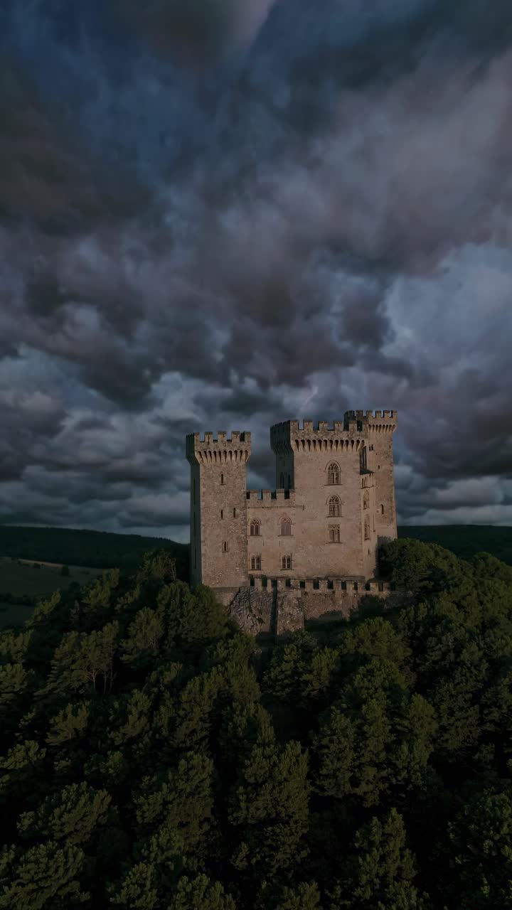 Dramatic aerial video shot of a medieval castle surrounded by dense forest, with stormy skies