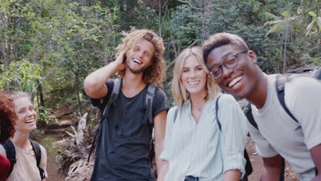 Portrait-Of-Smiling-Young-Friends-Hiking-Through-Countryside-Together