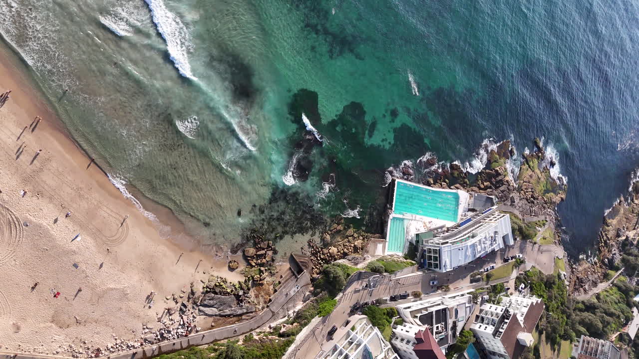Cinematic aerial view of Bondi Beach and ocean pool, highlighting the natural beauty of this iconic Australian coastal landmark. Rotating vertical drone footage.