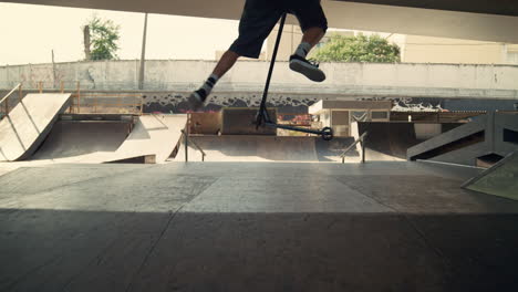 active boy jumping tricks on scooter at skatepark. rider flipping on scooter.