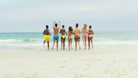 group of mixed-race friends running together on the beach 4k