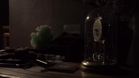 torsion clock spinning while sitting on a cluttered side table lit by a single lamp