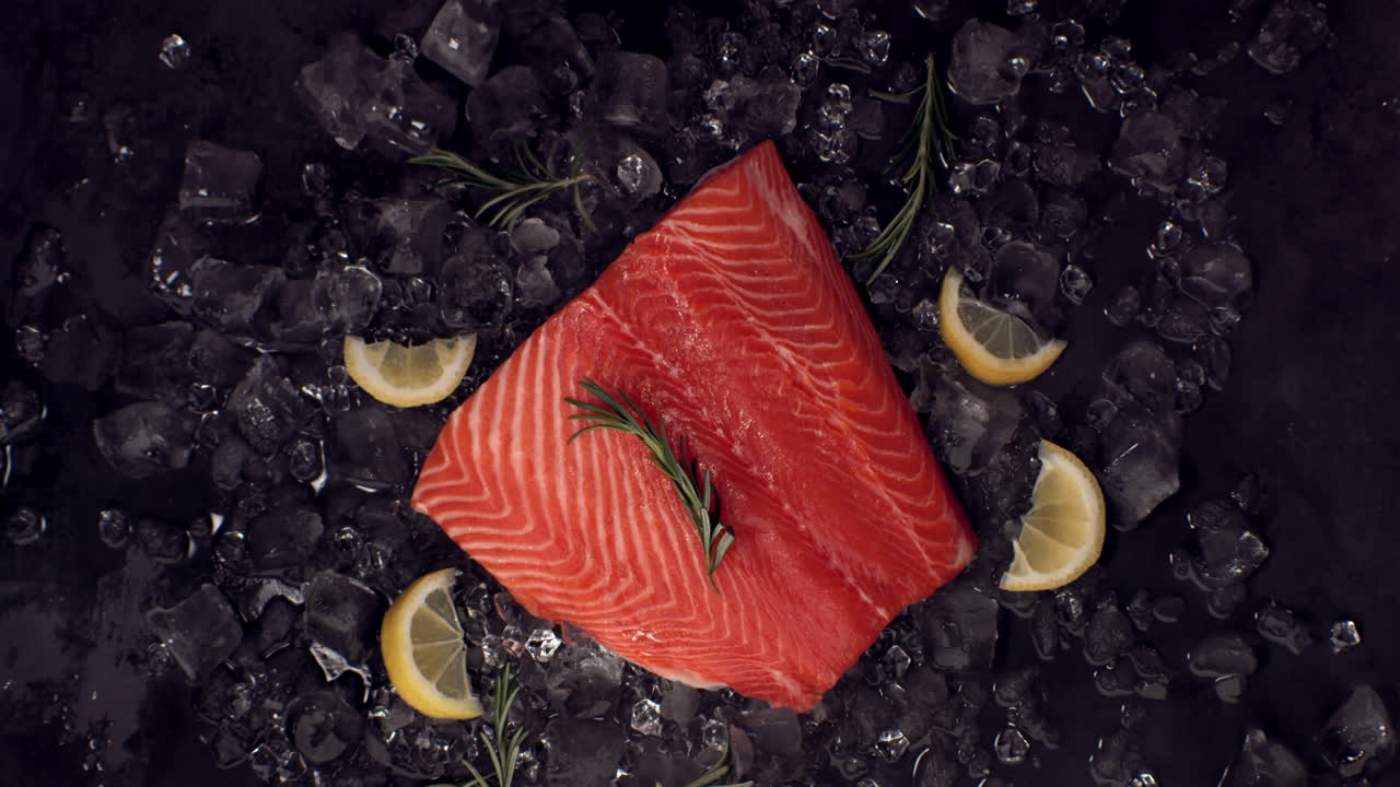 로즈마리 가지가 얼음 어리에 놓인 신선한 지 않은 연어 필레에 떨어지는 슈퍼 느린 동작 오버헤드 뷰, 고속 카메라로 촬영, 420fps