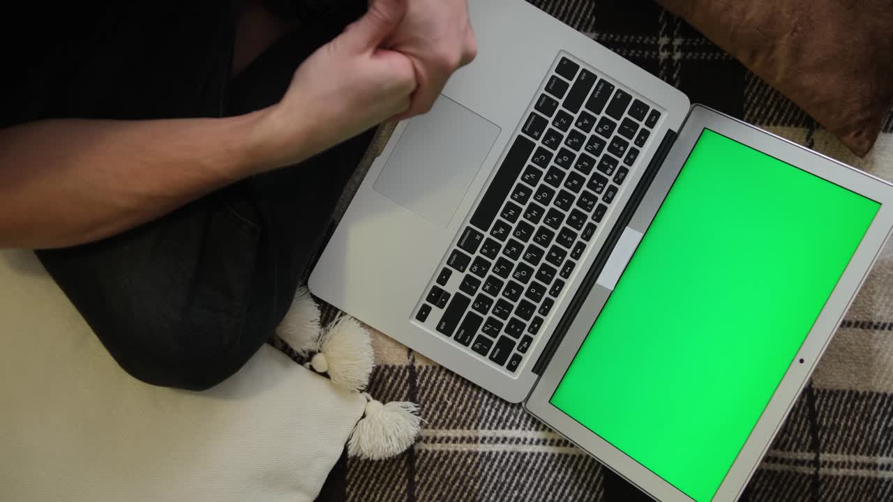 Una persona lavora da remoto. Schermo verde del laptop. Messa a fuoco morbida selettiva. Il concetto di didattica a distanza. Navigazione su Internet. Vista dall'alto.