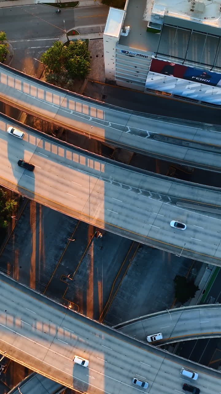 Intertwining roads on the freeways of Miami, Florida, USA from top. Drone descending above the speedways at sunset. Vertical video
