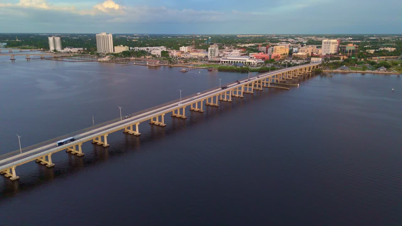 Aerial tracking shot of cars on bridge arriving north fort Myers in Florida. Early sunrise in America. Landscape and city houses in distance. Establishing footage