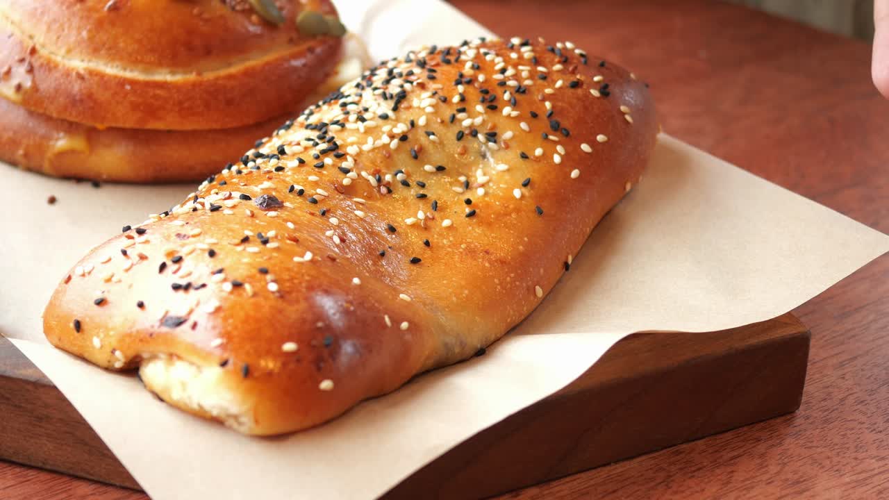 sosteniendo las manos y arreglando una variedad de productos horneados en una bandeja de madera con papel de pergamino