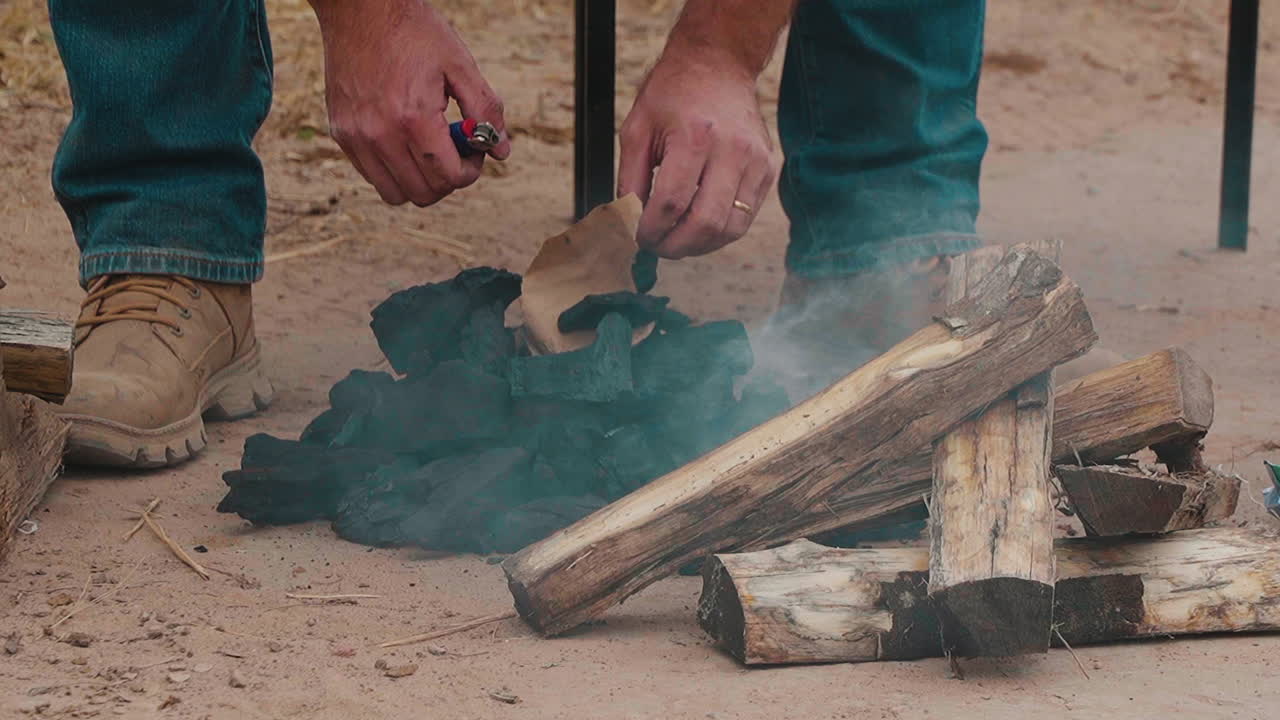 파라과이 의 바베큐 를 기 위해 나무 석탄 과 연료 를 회전 시키는 사람