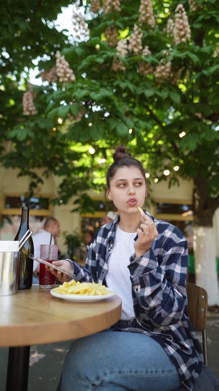 여자 가 김 을 먹고 야외 카페 에서 스마트폰 을 사용 하고 있다