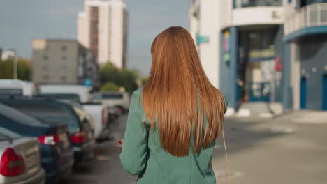 Restless-female-talks-on-phone-walking-past-parked-cars