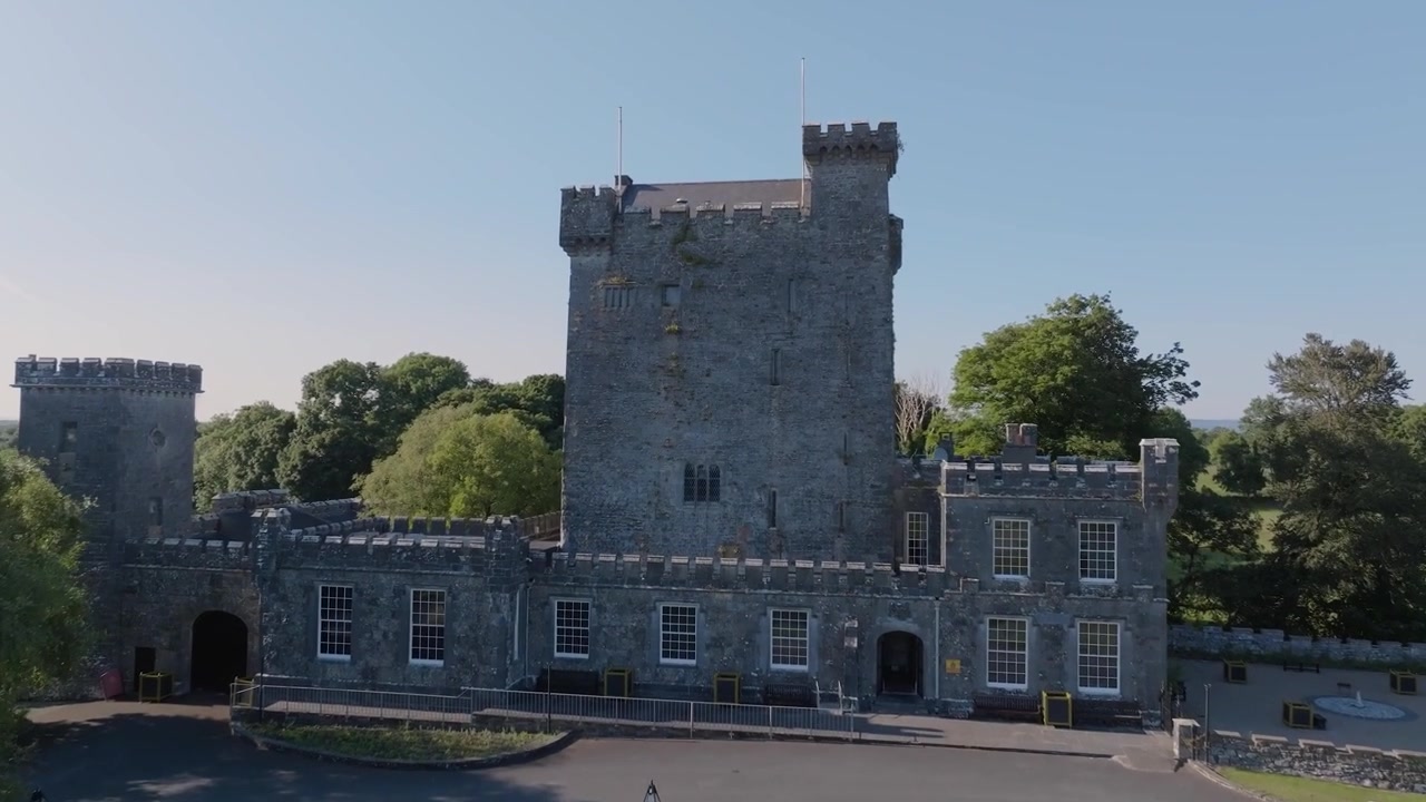 Il Castello di Knappogue si erge sopra prati aperti e alberi mentre un drone avanza sotto la luminosa luce estiva