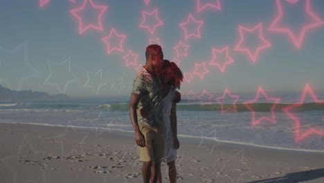 animation of neon stars changing colours over happy african american couple walking on beach