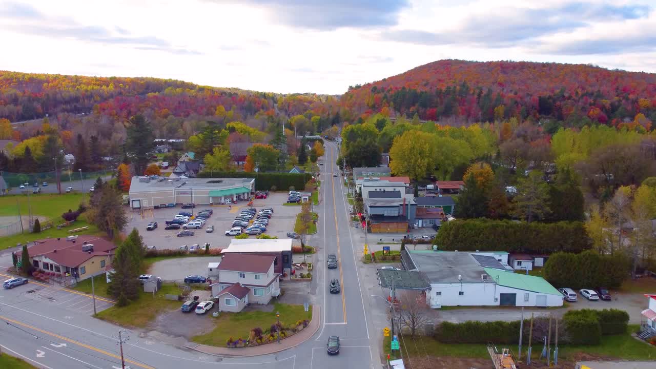 Intersection in a small rural town surrounded by fall colors and rolling hills, aerial