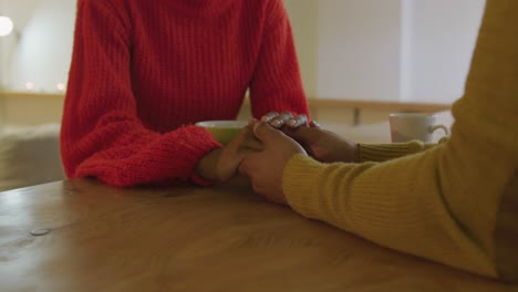 Millennial-couple-sitting-holding-hands-at-home-