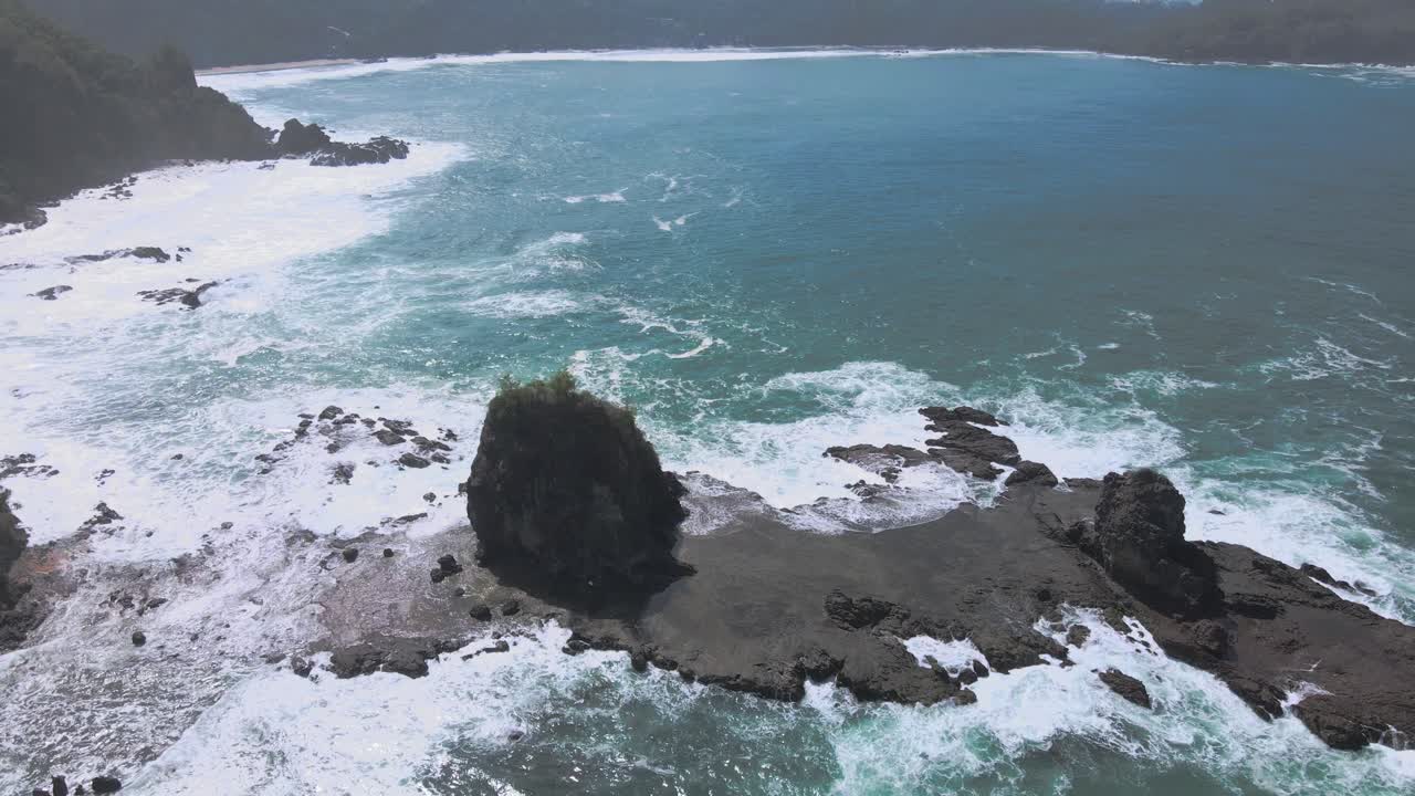 Bird's eye view of waves crashing on a coral island off the coast of Indonesia