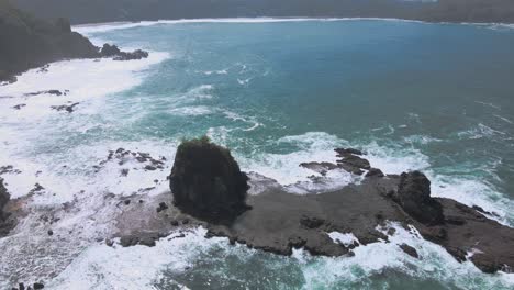 bird's eye view of waves crashing on a coral island off the coast of indonesia