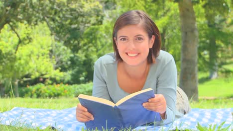 mujer joven leyendo un libro al aire libre