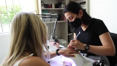 ethnic doing manicure to client and applying nail polish