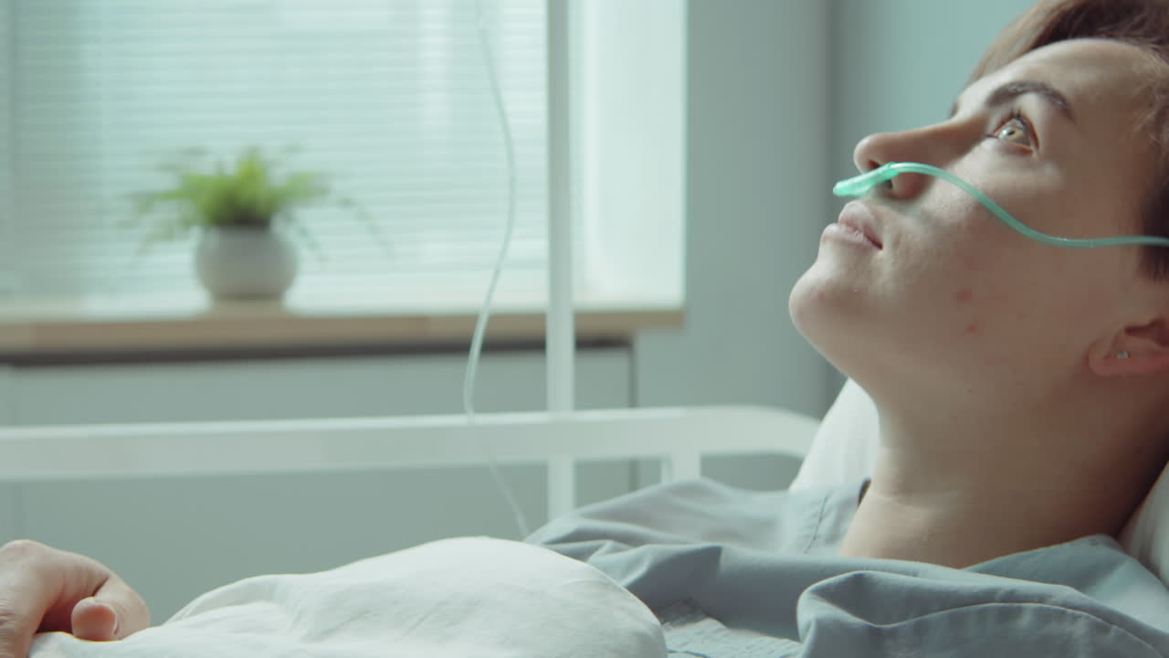 молодая женщина с носовой канюлой лежит в больничном отделении