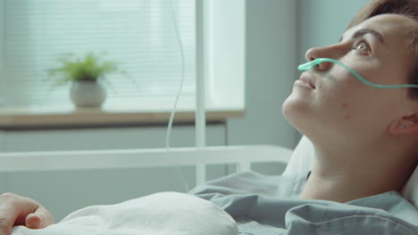 una mujer joven con una cánula nasal en la sala del hospital.