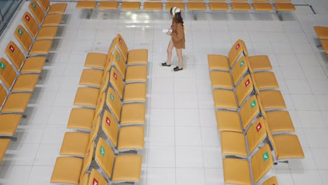 mujer asiática de 4k usando teléfono móvil mientras espera un vuelo en la puerta de embarque en la terminal del aeropuerto.