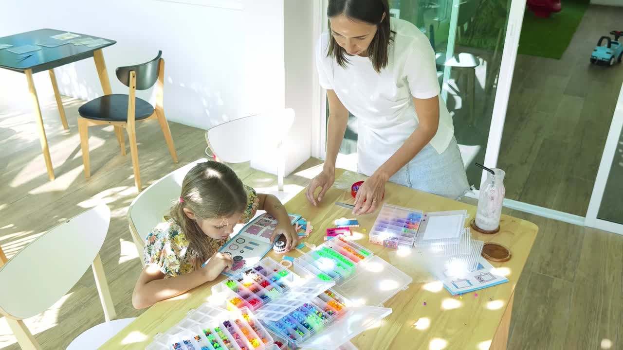 madre e hija haciendo actividad de perlas juntos